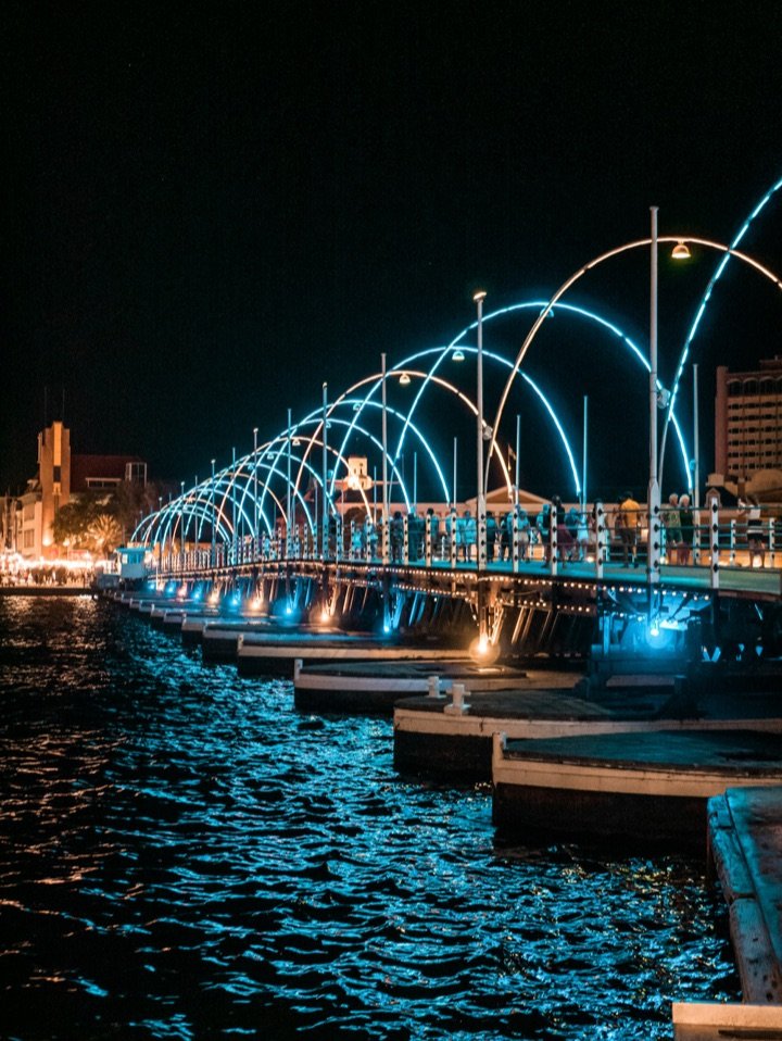 El puente flotante Reina Emma de Willemstad iluminado con arcos de luz de noche
