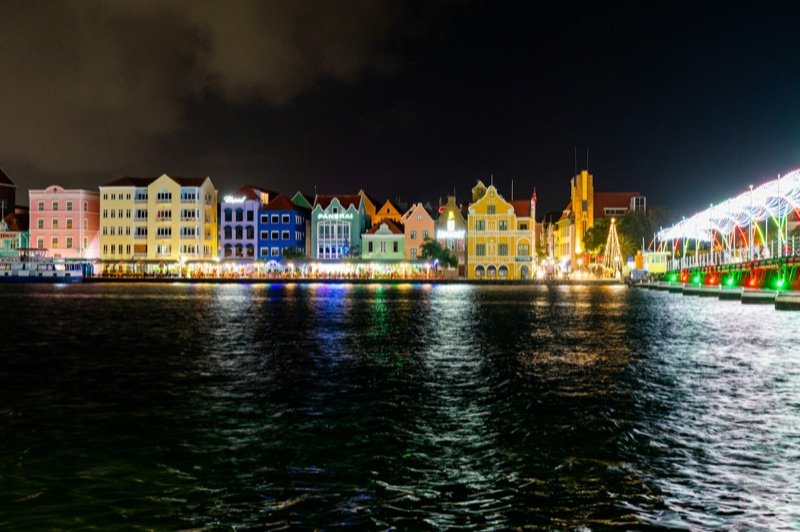 El malecón Handelskade de Willemstad iluminado de noche, reflejado en el puerto